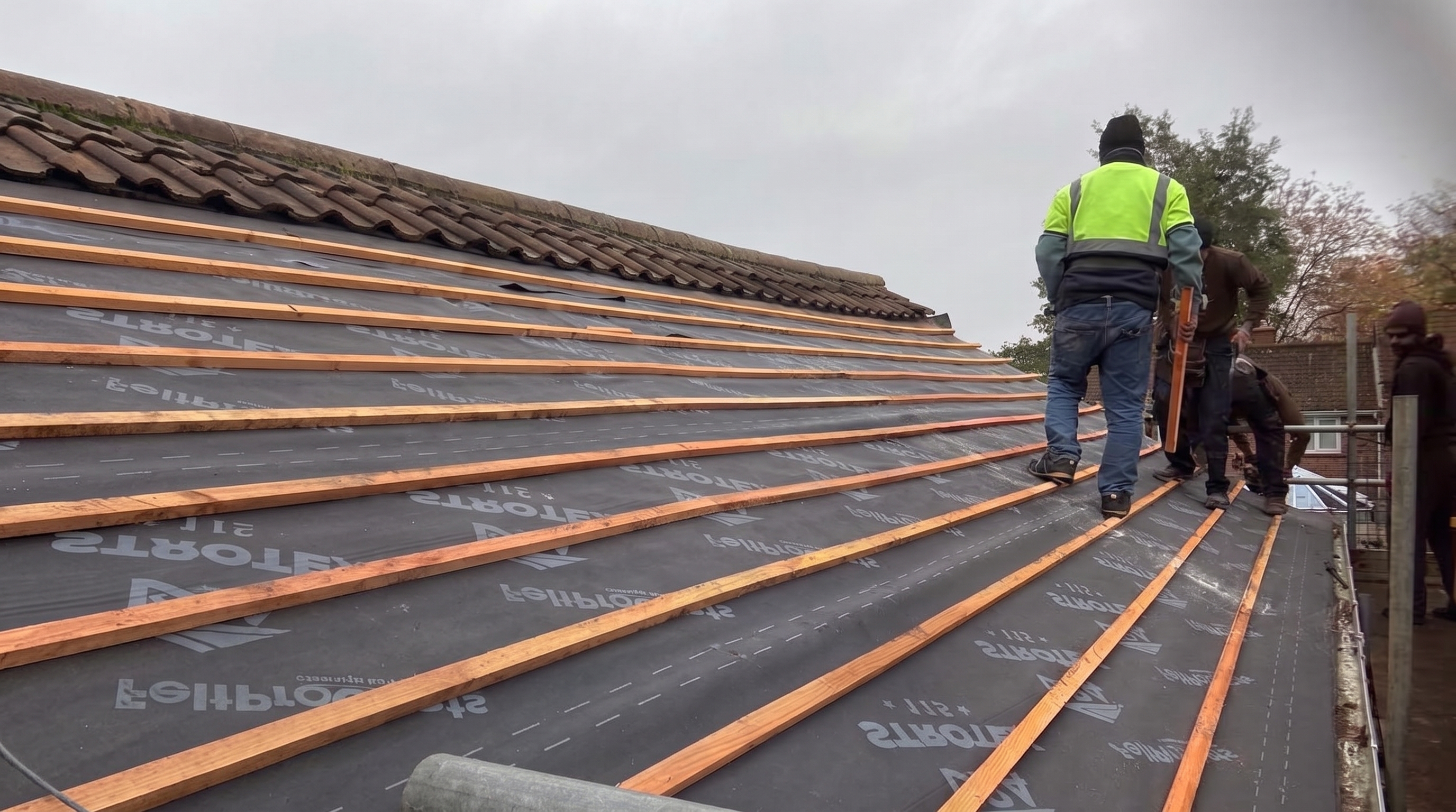 Roofers fitting new battens over breathable membrane on a pitched roof